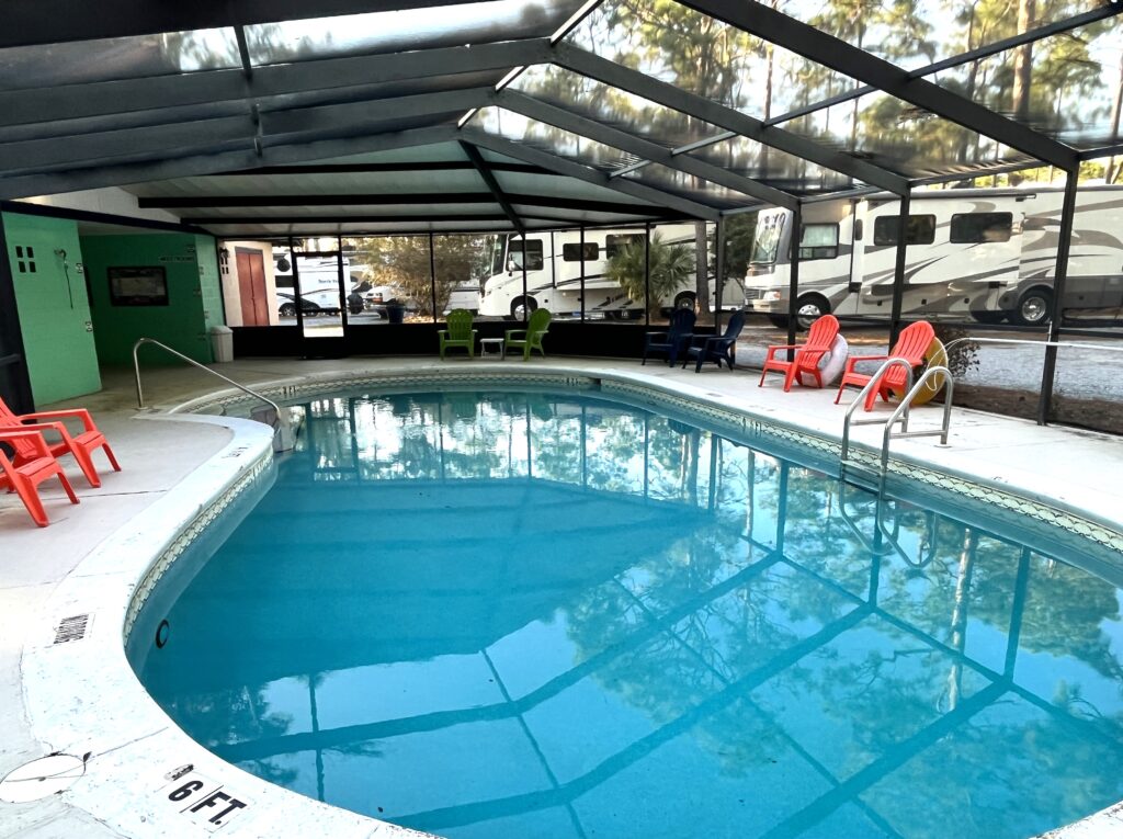 Freeform kidney shaped pool under a bird cage sits adjacent to showers and the laundry area